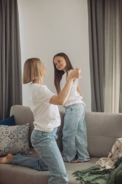 Neşeli anne küçük kızıyla kanepede gülüyor, neşeli genç anne sevimli bebekle eğleniyor..