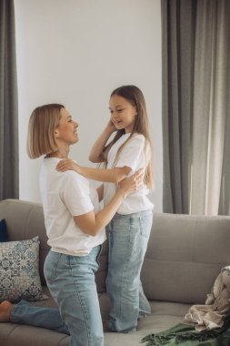 Neşeli anne küçük kızıyla kanepede gülüyor, neşeli genç anne sevimli bebekle eğleniyor..