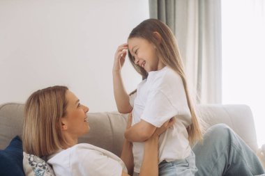 Anne ve kızı evde oyun oynayıp, sarılarak vakit geçiriyorlar..