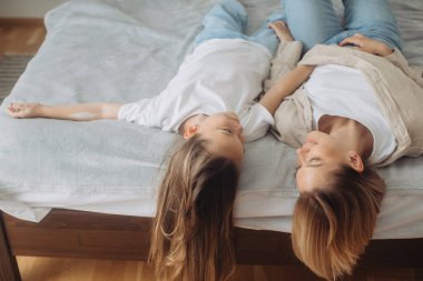 Mutlu anne-kız eğleniyor ve evde yatakta birlikte oynuyorlar..