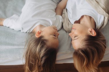 Mutlu anne-kız eğleniyor ve evde yatakta birlikte oynuyorlar..