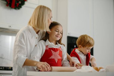 Noel, anne ve çocuklar mutfakta kurabiye yapıyorlar. Anne çocuklara kurabiye pişirmeyi öğretir..