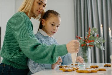 Anne ve kız mutfakta Noel kurabiyeleri süslüyor..