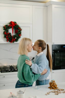 Mutlu anne ve kız, Noel kurabiyelerini pişirdikten sonra mutfakta sarılıyorlar..