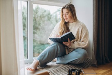 Genç ve güzel bir bayan öğrenci evde yaratıcı dergiler yazıyor..