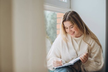 Genç ve güzel bir bayan öğrenci evde yaratıcı dergiler yazıyor..