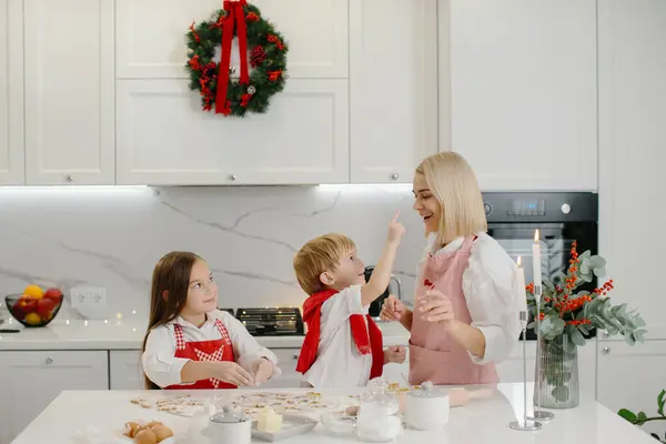 快乐的母亲和孩子们在厨房桌子边做圣诞饼干的时候玩饼干面团 — 图库照片