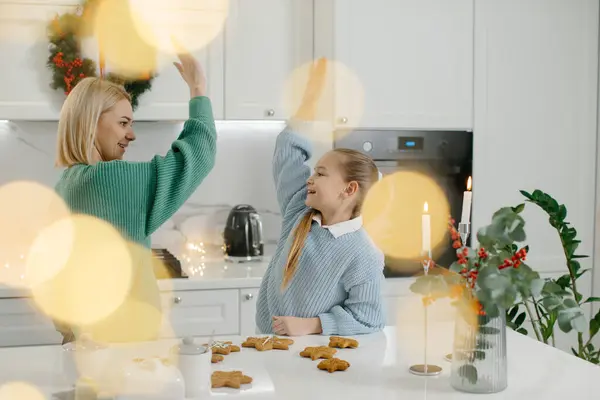 かわいい小さな女の子と彼女の美しい母親は 自宅でクリスマスクッキーを作っている間 高いファイブと笑顔を与えます — ストック写真