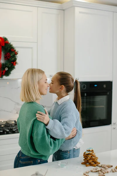 ハッピーマザーと娘はクリスマスクッキーを焼いた後にキッチンで抱擁しています — ストック写真