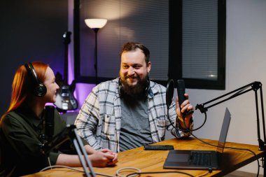 Bir internet blogcusu stüdyoda bir misafirle podcast bölümü çekiyor. İçerik yaratıcısı sosyal ağlardan canlı bir konuşma yayınlıyor. Radyo sunucuları stüdyoda canlı yayında..