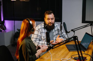Radyo sunucuları akşam programı sırasında iletişim kuruyor. Ev stüdyosunda yeni bir podcast bölümü kaydediliyor..