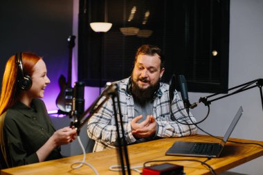 İnternetteki bir sunucu, bir ev stüdyosunda bir misafirle birlikte bir podcast kaydediyor. Mutlu adam ve kadın internet yayını sırasında birlikte gülüyorlar..