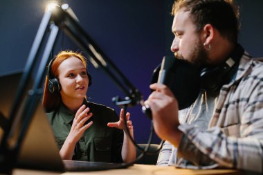 Adam internet yayınında profesyonel mikrofon ve ses karıştırıcı kullanarak kadınla sohbet ediyor. Çevrimiçi radyo istasyonu sunucusu. Gece yarısı talk show 'unda podcast röportajı yapan konuk..
