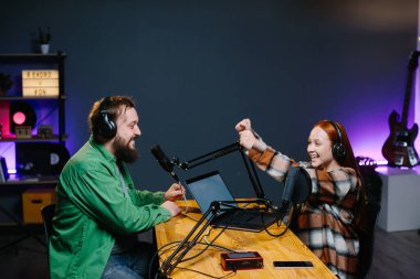 Bir podcast sunucusu ve bir konuk ev stüdyosunda canlı yayında sohbet ederken eğleniyorlar..