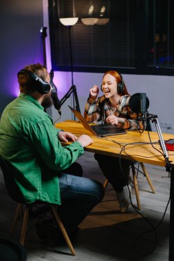Bir podcast sunucusu ve bir konuk ev stüdyosunda canlı yayında sohbet ederken eğleniyorlar..