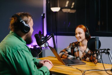 Bir podcast sunucusu ve bir konuk ev stüdyosunda canlı yayında sohbet ederken eğleniyorlar..
