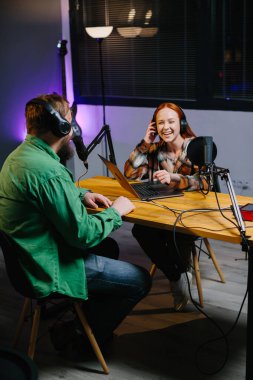 Bir podcast sunucusu ve bir konuk ev stüdyosunda canlı yayında sohbet ederken eğleniyorlar..