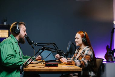 Bir podcast sunucusu ve bir konuk ev stüdyosunda canlı yayında sohbet ederken eğleniyorlar..