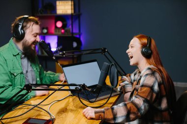 Bir podcast sunucusu ve bir konuk ev stüdyosunda canlı yayında sohbet ederken eğleniyorlar..