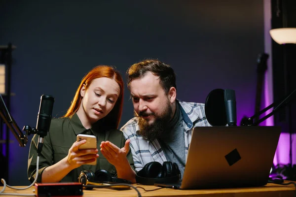 Online show hosts in a home studio. Online bloggers, with a phone in their hands, read the comments of viewers.