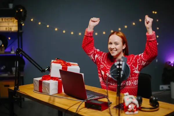 女の子のブロガーがチャンネルでクリスマスプレゼントをしている 家のスタジオで彼女の手で贈り物をクリスマスのセーターで女の子の肖像画 — ストック写真