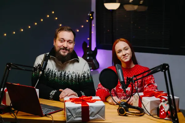 数人のブロガーがチャンネルでクリスマスプレゼントをしています クリスマスセーターのラジオプレゼンターは リスナーの間で贈り物のラッフルを行います — ストック写真