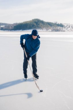 Kış mevsiminde donmuş gölde hokey oynayan son sınıf öğrencisi..