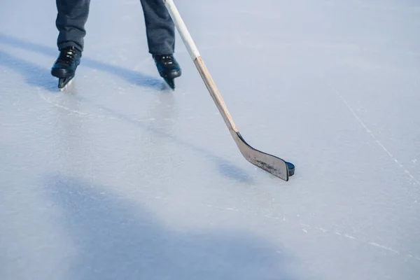 Close-up of hockey stick and puck on ice field.