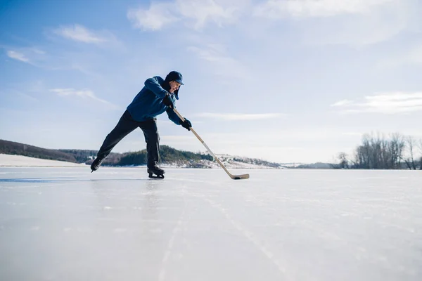 Starszy Mężczyzna Ćwiczy Uderzanie Krążka Kijem Hokejowym Zamarzniętym Jeziorze Zimie — Zdjęcie stockowe