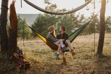 Mutlu çift, dışarıda gün batımının tadını çıkarırken hamakta dinleniyor..