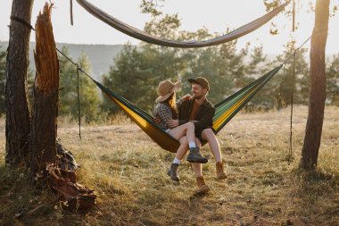 Birbirine aşık bir çift, gün batımında bir hamakta dinlenir..