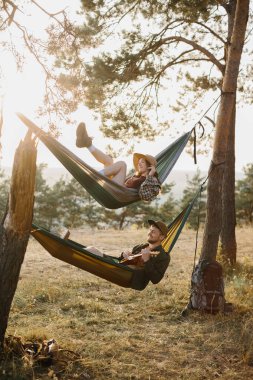 Bir erkek ve bir kız gün batımında bir çam ormanında hamaklarda dinleniyorlar. Dağlarda yürüyüş yaptıktan sonra hamaklarda dinlenen bir çift, ukulele çalan bir adam..