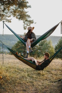 Gençler dağlardaki hamaklarda dinleniyor. Rahatlama ve doğayla bütünleşme kavramı..