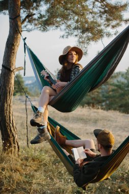 Estetik dinlenme. Güzel bir genç kız ve erkek arkadaşı gün batımında hamakta dinleniyorlar..