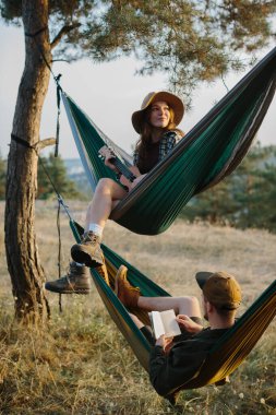 Estetik dinlenme. Güzel bir genç kız ve erkek arkadaşı gün batımında hamakta dinleniyorlar..