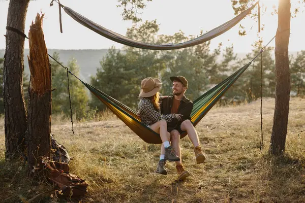 Happy couple in love enjoying the sunset outdoors while relaxing in a hammock.