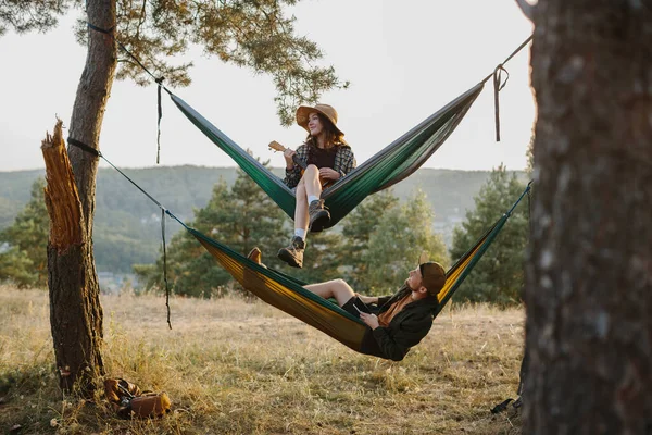 Genç bir adam ve güzel genç bir kadın dağlarda hamaklarda dinleniyorlar. Rahatlama ve doğayla bütünleşme kavramı..