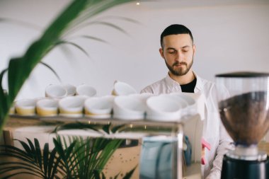 Espresso makinesinin yanında bir barista lezzetli bir kahve hazırlar. Genç bir adam bir kafede kahve hazırlıyor..