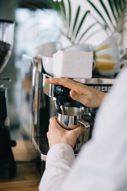 Bir barista espresso makinesi kullanarak kapuçino için süt hazırlar. Kafede kahve hazırlayan bir adamın yakın çekimi..