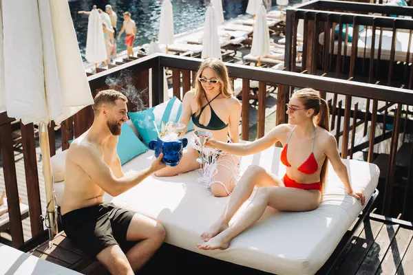 Neşeli bir arkadaş grubu havuz başında kokteyllerle rahatlıyor..