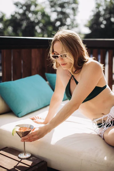 穿着时髦泳衣和太阳镜的年轻女子在暑假喝鸡尾酒 无忧无虑的富裕生活方式 — 图库照片