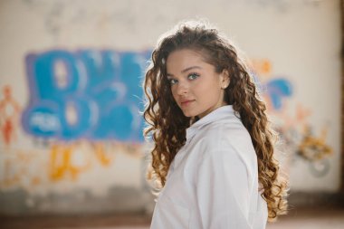 Grafiti arka planına karşı sokakta poz veren hoş, genç bir kadın..