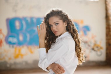 Grafiti arka planına karşı sokakta poz veren hoş, genç bir kadın..