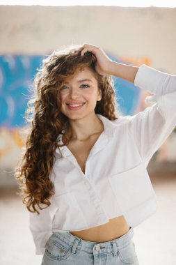 Grafiti arka planına karşı sokakta poz veren hoş, genç bir kadın..