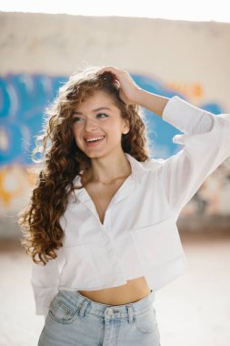 Grafiti arka planına karşı sokakta poz veren hoş, genç bir kadın..