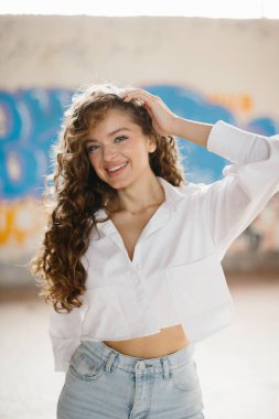 Grafiti arka planına karşı sokakta poz veren hoş, genç bir kadın..
