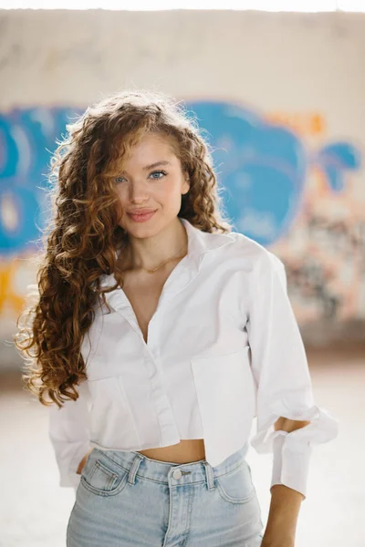 Grafiti arka planına karşı sokakta poz veren hoş, genç bir kadın..