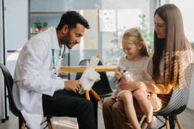 Mutlu küçük kız, anne ve doktor oyuncak ve nörologların çekiciyle oyun oynuyorlar..