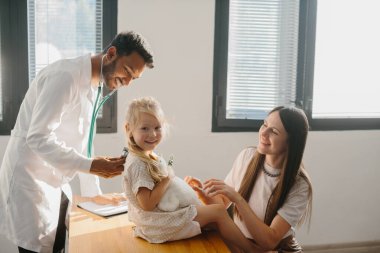Annesiyle birlikte anaokulu çağındaki bir kız bir çocuk doktoru tarafından muayene ediliyor. Genç bir adam, bir pulmonolog, falendoskop kullanarak muayene ediyor..