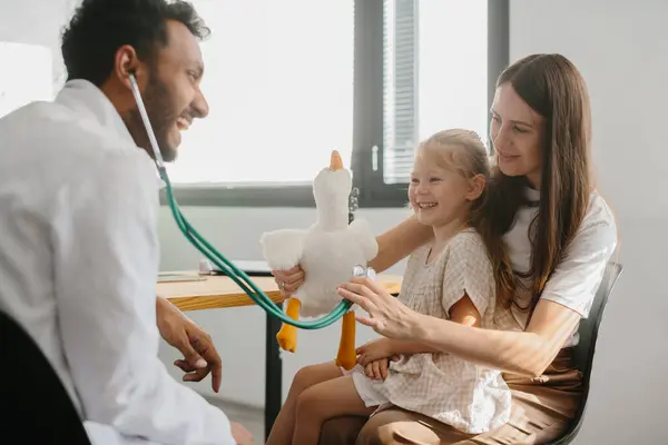 小児科医は 子供との接触 良好な関係を確立する 幸せな少女 おもちゃとスタスコープで楽しいゲームをする母親と家族の医師 — ストック写真